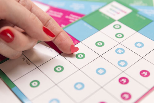 joyful couple's romance bingo, close up of a woman placing a heart sticker on the bingo card