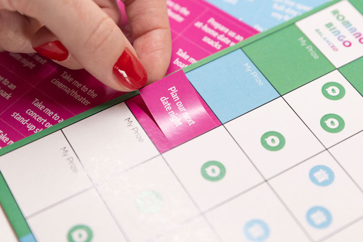joyful couple's romance bingo, close up of a woman placing a prize sticker on the bingo card