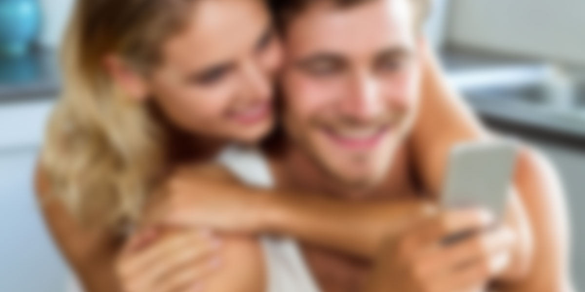 blurred image of a couple looking at their phone, both are happy and smiling